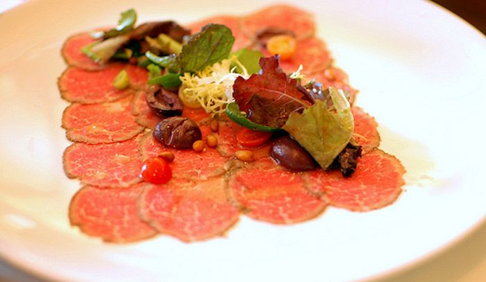 Carpaccio di vitello con olive e pinoli